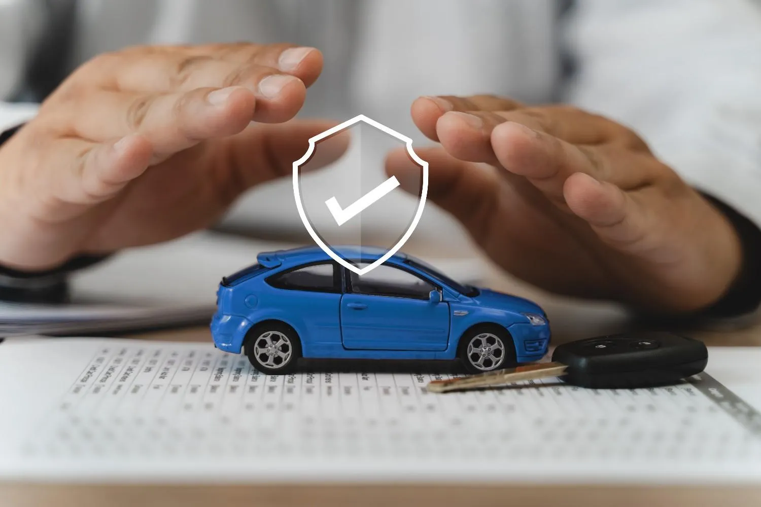 Hands shielding a car alongside a set of keys and a policy form